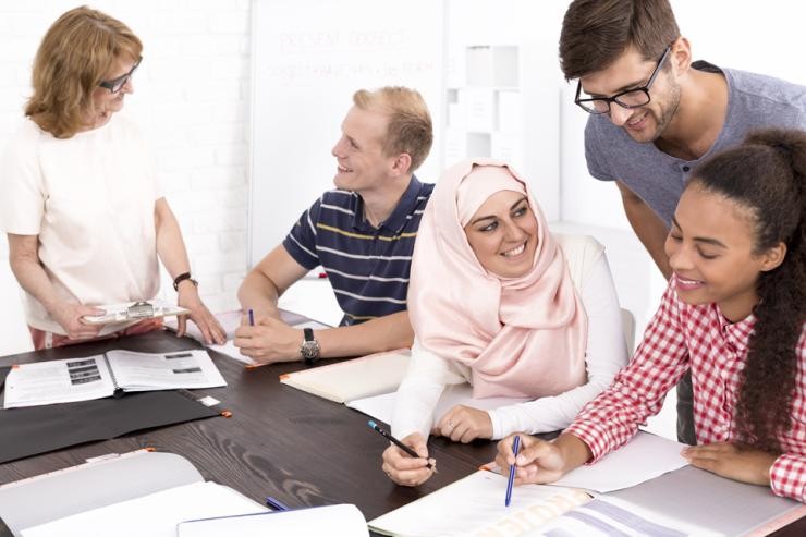 Tätikeiten in der Praxis beim Studium Soziale Arbeit, Arbeit, Integration, Soziale Sicherung Eine Anleitung erklärt einem Studierenden etwas und Studierende besprechen eine Aufgabe